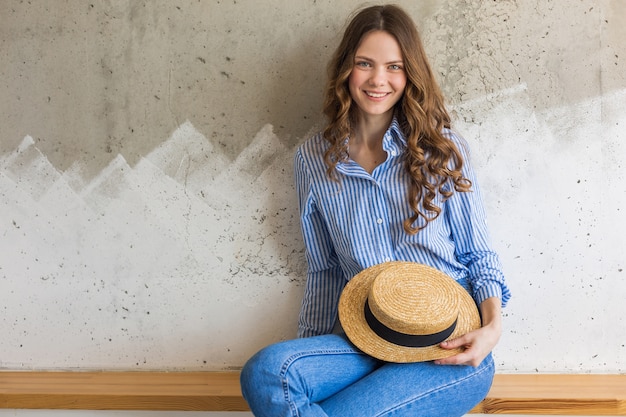 Jeune femme élégante et séduisante assise au mur