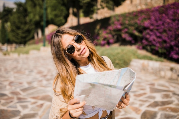 Photo gratuite jeune femme élégante tenant la carte debout dans le parc