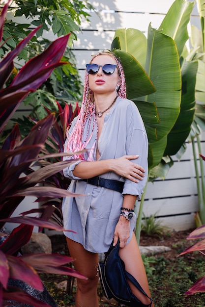 Photo gratuite jeune femme élégante avec des tresses violettes roses et sac de taille noir posant en plein air