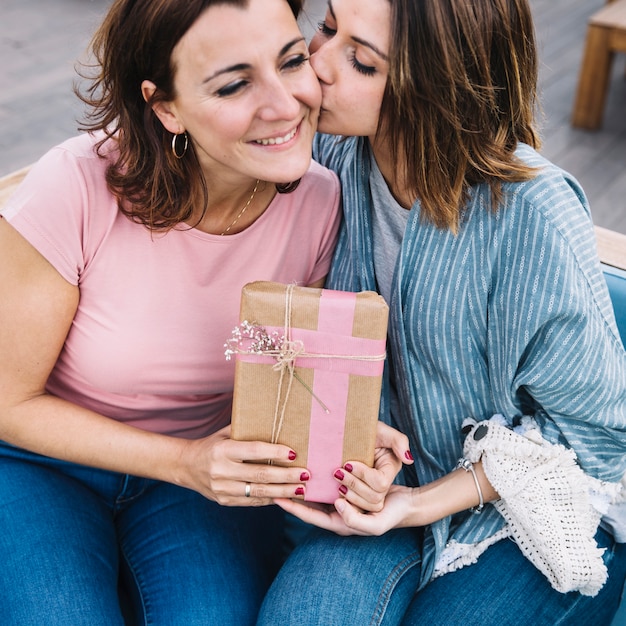 Jeune femme embrasser adulte avec un cadeau