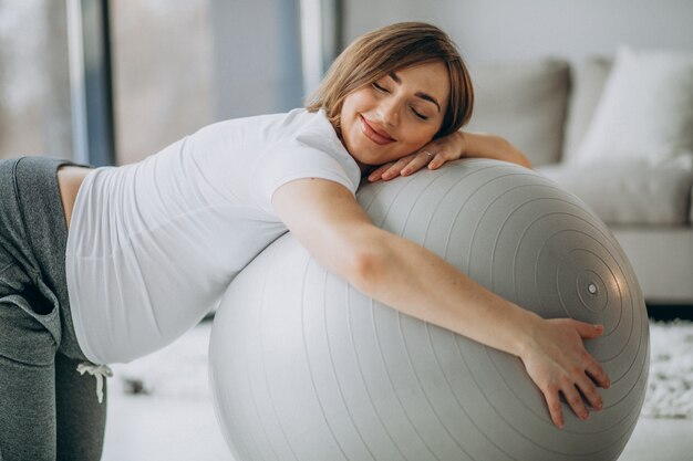 Jeune femme enceinte, faire du yoga avec ballon en forme à la maison