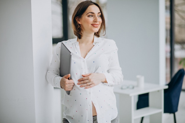 Jeune femme enceinte travaillant sur ordinateur hors du bureau