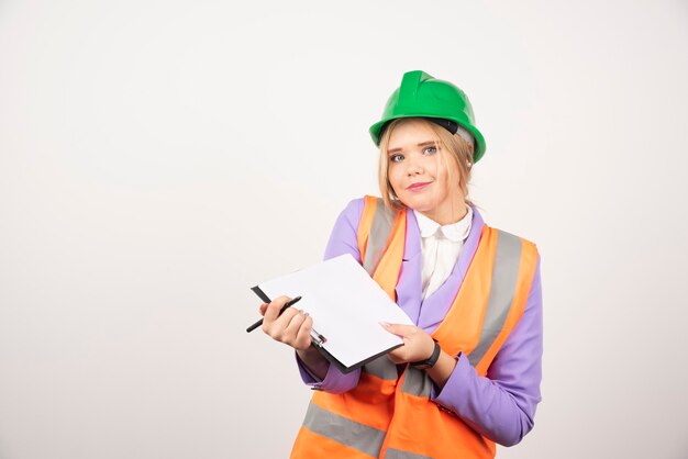 Jeune femme entrepreneur avec casque vert a ouvert le presse-papiers sur blanc.