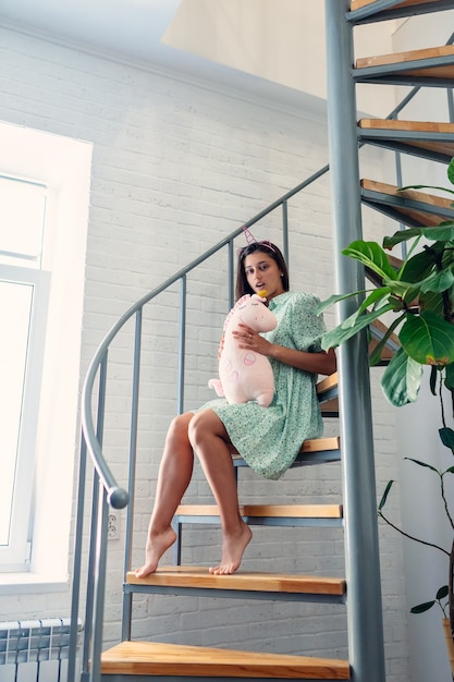 Jeune femme sur des escaliers en bois dans une maison moderne.