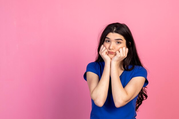 Jeune femme essayée tenant ses mains sur son visage et regardant la caméra Photo de haute qualité