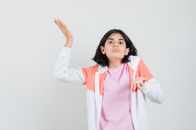 Jeune femme étalant ses paumes ouvertes en veste, chemise rose et à la recherche d'impuissance.