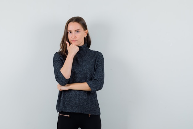 Jeune femme étayant le menton sur place en chemise