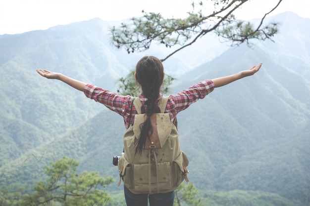 La jeune femme étendit ses bras au sommet de la colline dans une forêt tropicale avec des sacs à dos dans la forêt. Aventure, Randonnée.