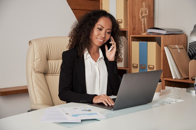 Jeune, femme ethnique, parler téléphone, dans, bureau