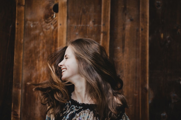 Une jeune femme étonnante tourne les cheveux debout devant un vieux mur en bois
