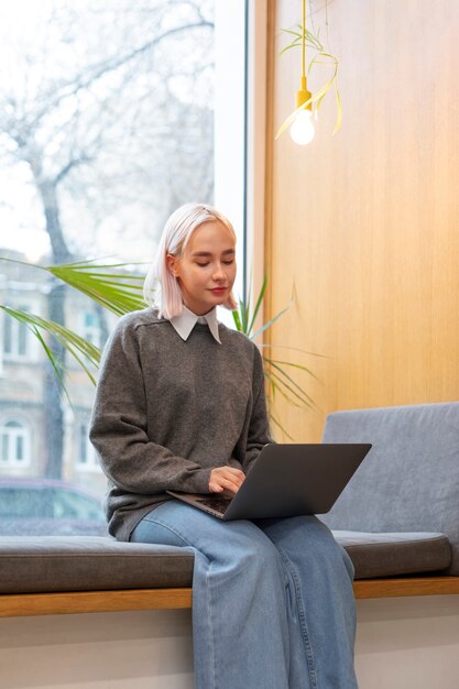 Jeune femme étudiant dans une bibliothèque tout en utilisant un ordinateur portable