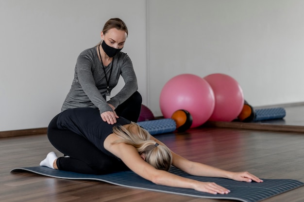 Jeune femme exerçant au gymnase aidé par l'entraîneur