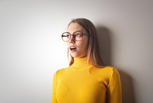 jeune femme à l'expression étonnée appuyée contre un mur