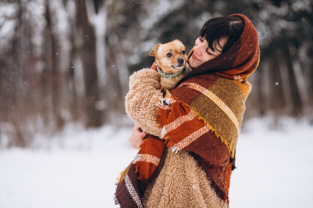 Jeune femme à l'extérieur du parc avec son petit chien en hiver