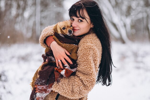 Jeune femme à l'extérieur du parc avec son petit chien en hiver