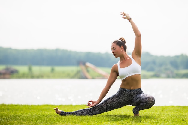 Jeune femme faire du yoga pose au parc le matin avec la lumière du soleil