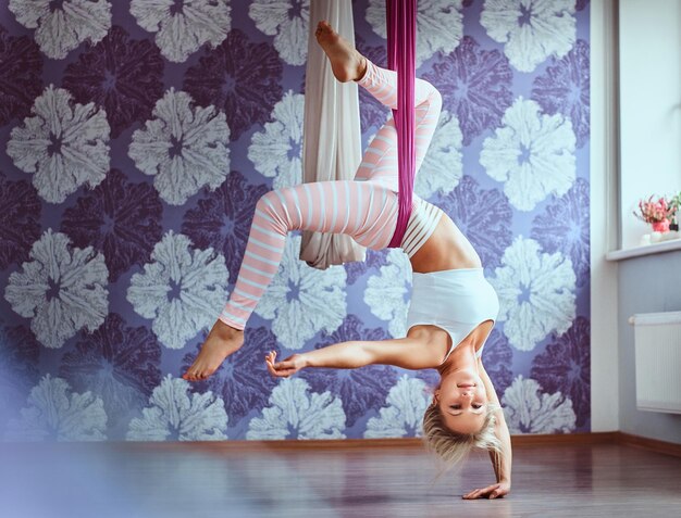 Jeune femme faisant du yoga aérien dans un hamac violet dans un club de fitness.