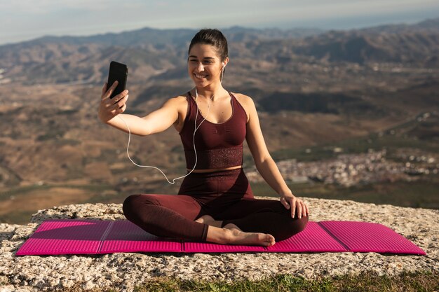 Jeune femme faisant du yoga sur maquette de montagne