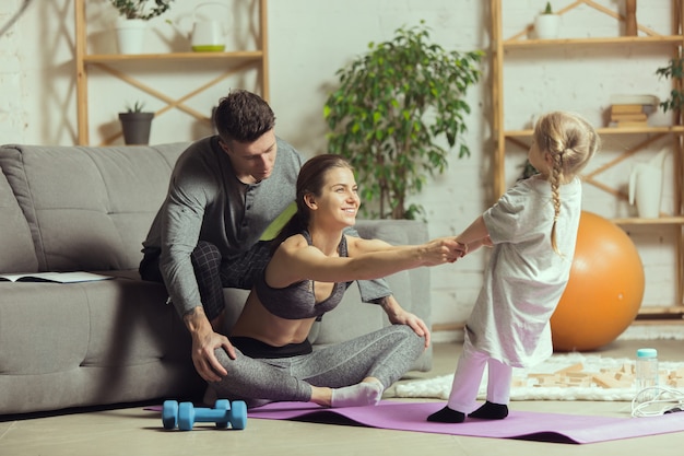 Jeune femme faisant du yoga avec sa fille et son mari