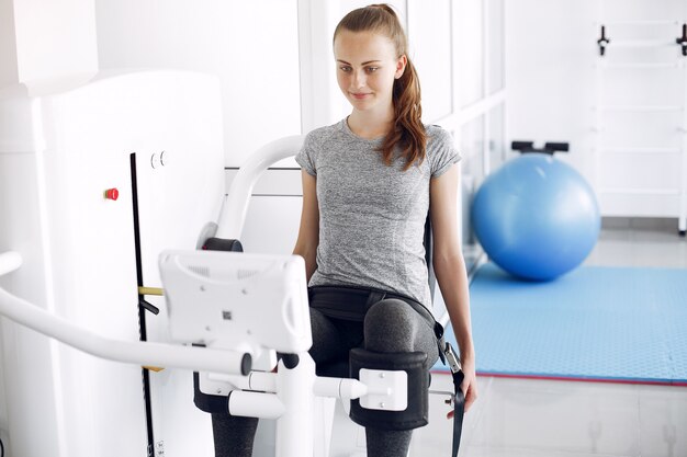 Jeune femme faisant des exercices sur simulateur dans la salle de phisiotherapy