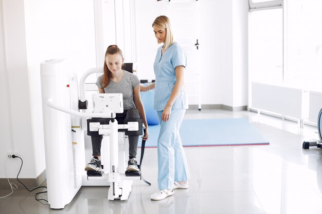 Jeune femme faisant des exercices sur simulateur avec thérapeute en salle de sport