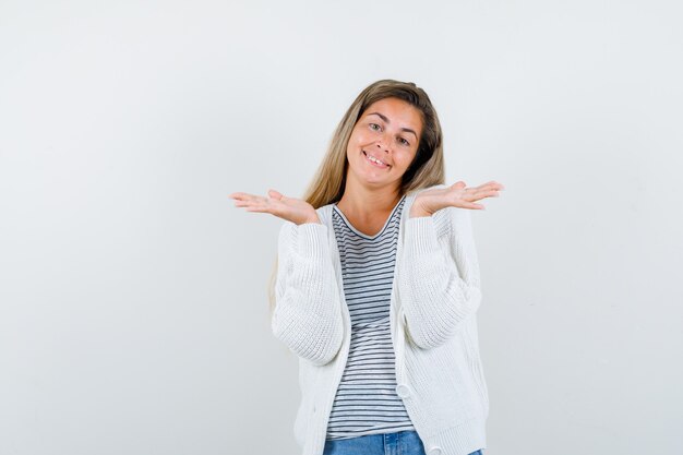 Jeune femme faisant un geste de bienvenue en t-shirt, veste et à la joyeuse. vue de face.