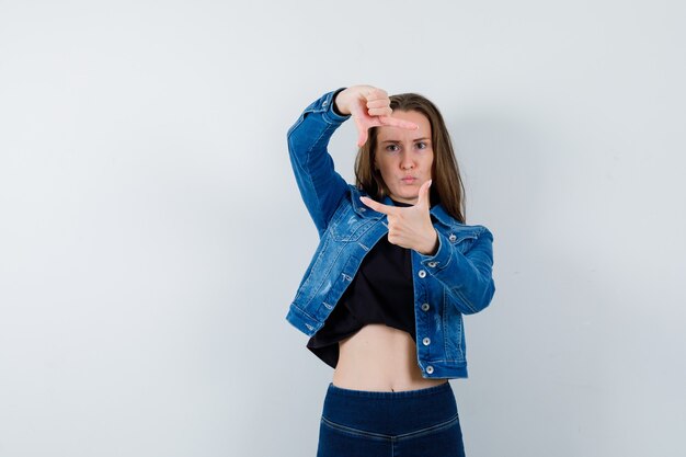 Jeune femme faisant un geste de cadre en chemisier et ayant l'air confiant. vue de face.