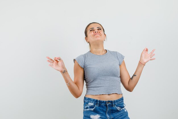 Jeune femme faisant la méditation avec les yeux fermés en t-shirt, short et à la paix