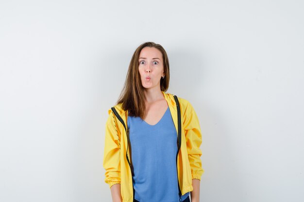 Jeune femme faisant la moue en t-shirt, veste et l'air surpris, vue de face.