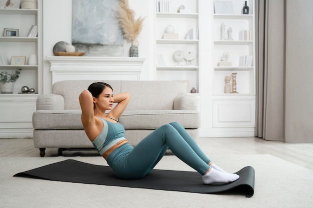 Photo gratuite jeune femme faisant son entraînement à la maison sur un tapis de fitness