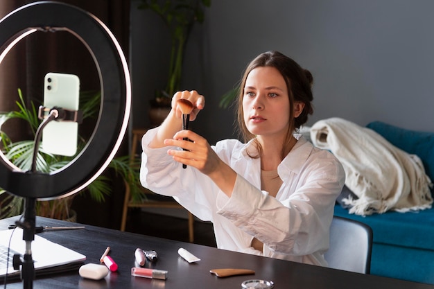 Jeune femme faisant un vlog de maquillage avec son smartphone