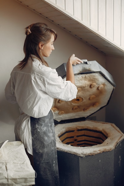 Photo gratuite jeune femme fait de la poterie en atelier