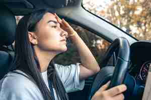 Photo gratuite une jeune femme fatiguée, chauffeur de voiture, souffrant de maux de tête, de migraines, conduisant un véhicule.