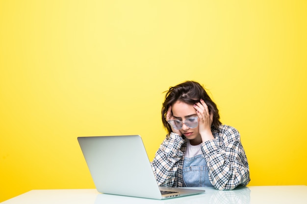 Jeune femme fatiguée devant un ordinateur portable isolé