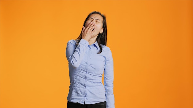 Photo gratuite une jeune femme fatiguée qui bâille et se comporte paresseusement devant la caméra. elle s'endort presque en studio et se sent extrêmement surchargée de travail. un adulte philippin est épuisé par la fatigue et la somnolence.