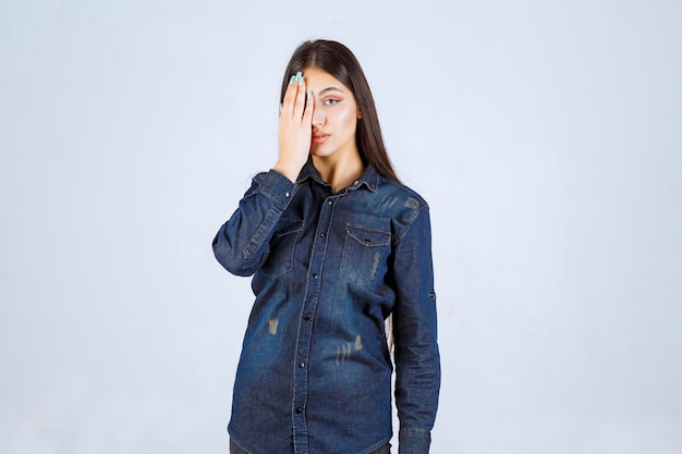 Photo gratuite jeune femme fermant les yeux ou une partie du visage et regardant à travers ses doigts