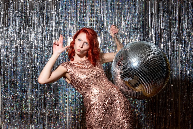 Jeune femme en fête avec boule disco sur des rideaux lumineux