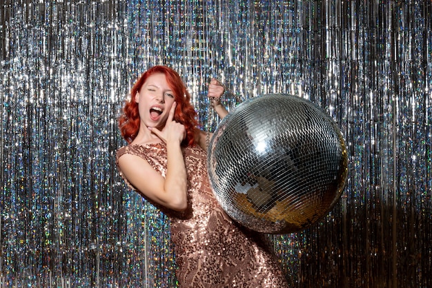 Jeune femme en fête avec boule disco sur des rideaux lumineux