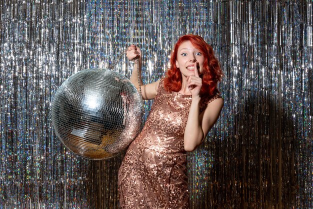 Jeune femme en fête avec boule disco sur des rideaux lumineux