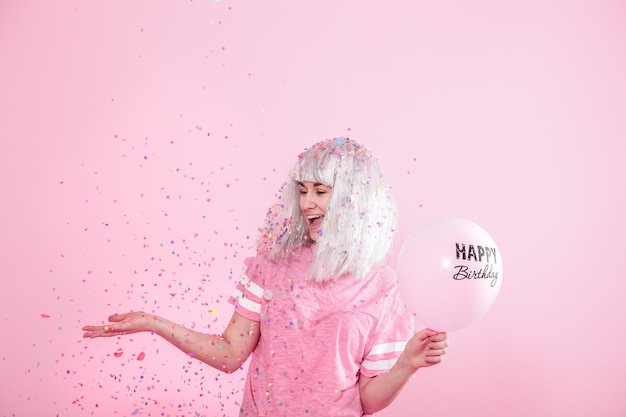 Jeune femme ou fille avec des ballons joyeux anniversaire. Jette des confettis d'en haut. Concept de vacances et de fête.
