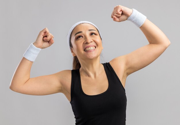 Jeune femme fitness avec bandeau et brassards levant les poings heureux et excité