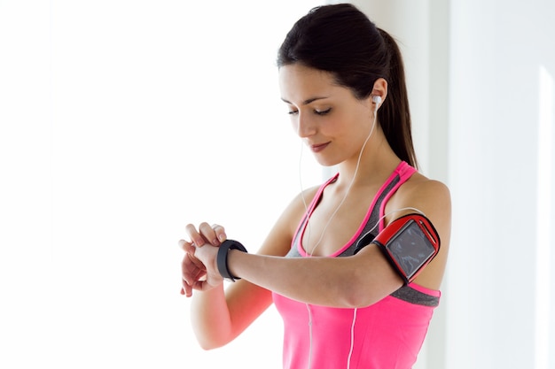 Une jeune femme de fitness regarde sa montre intelligente en prenant une pause.