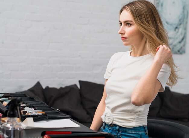 Jeune femme fixant sa coiffure en studio