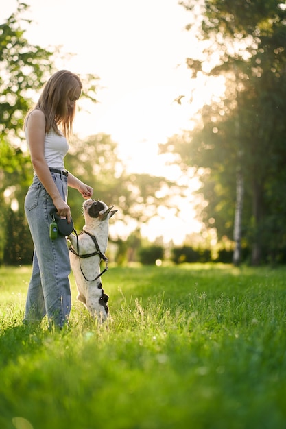 Jeune femme formation bouledogue français dans le parc