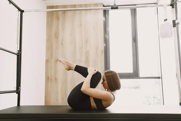 Jeune femme en forme s'entraînant dans une salle de sport. Femme portant des vêtements de sport noirs. Fille caucasienne qui s'étend avec de l'équipement.