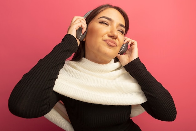 Jeune femme avec un foulard blanc et un casque heureux et positif en profitant de sa musique préférée