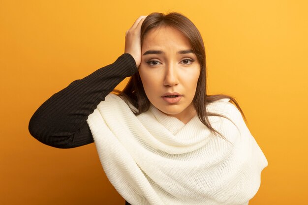 Jeune femme avec un foulard blanc à la confusion avec la main sur sa tête