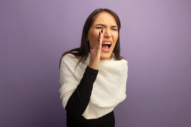 Jeune femme avec foulard blanc criant avec la main près de la bouche