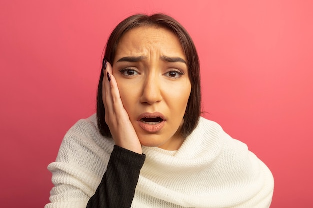 Jeune femme avec un foulard blanc avec expression de confusion avec la main sur son visage