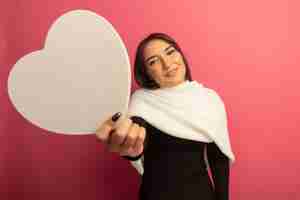 Photo gratuite jeune femme avec un foulard blanc montrant coeur en carton souriant avec amour